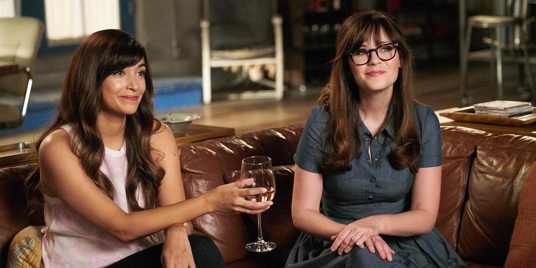 Jess and Cece sitting on a couch and drinking wine in New Girl