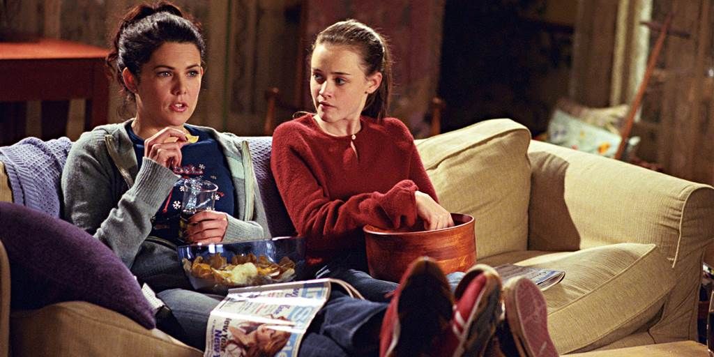 Lorelai and Rory on couch eating snacks in Gilmore Girls