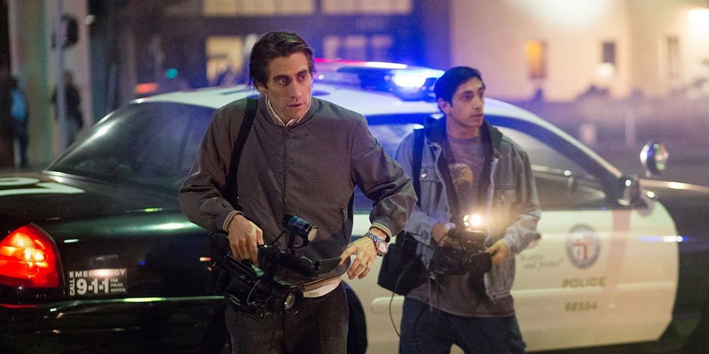Lou runs past a police car with a camcorder in Nightcrawler