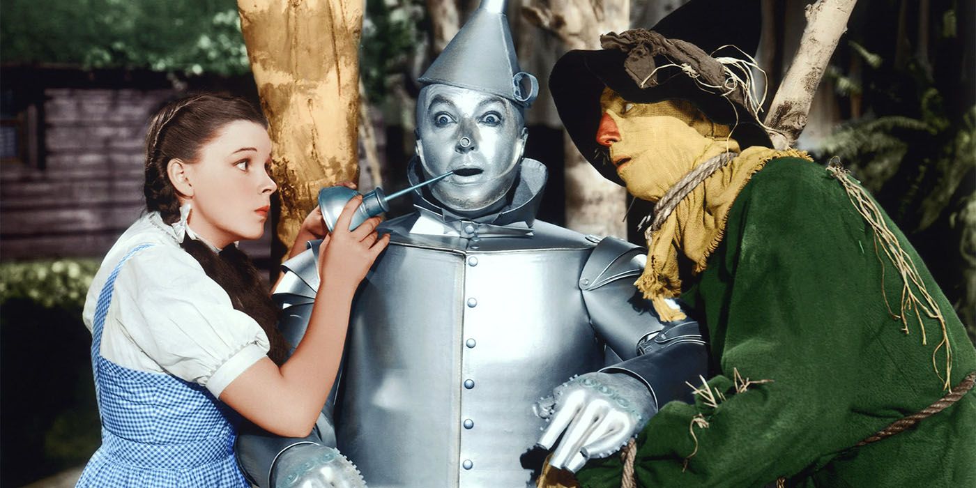 Dorothy, the Tin Man, and Scarecrow conversing about something in The Wizard of Oz