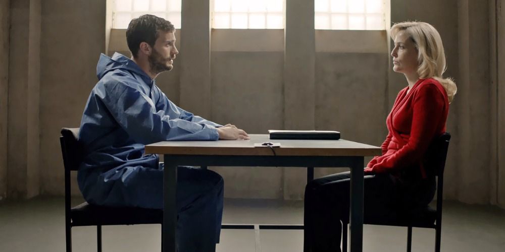 Man and woman sitting at prison table talking to each other.