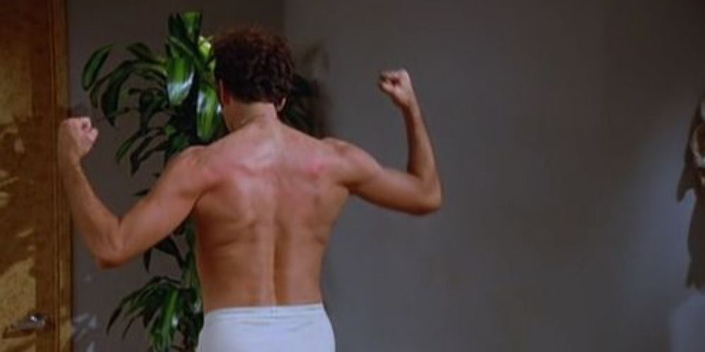 Kramer shirtless striking a pose and flexing his biceps