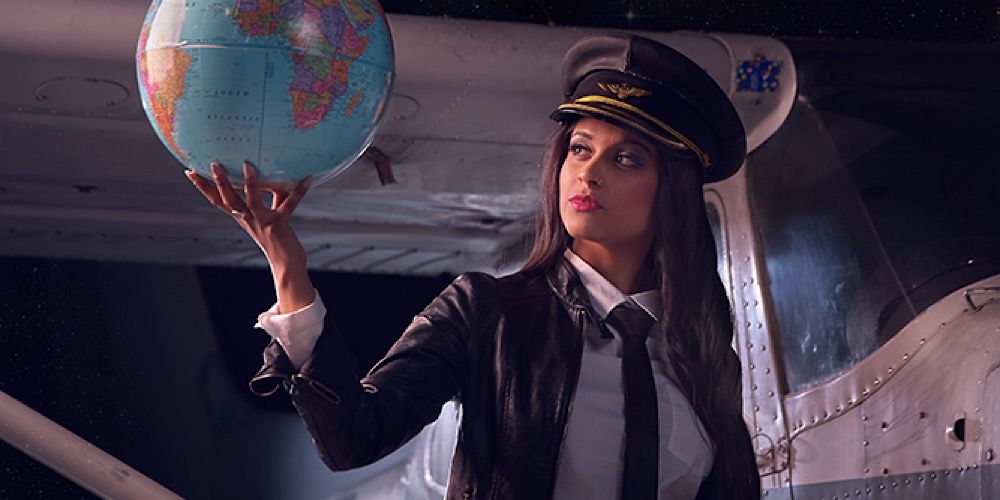 Lilly Singh dressed as a pilot and holding a globe