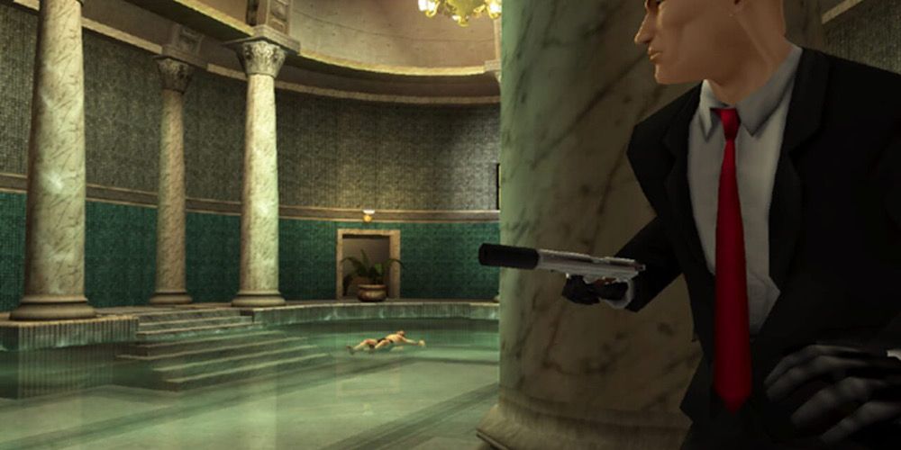 Agent 47 hides behind a pillar as a dead body lays in a swimming pool
