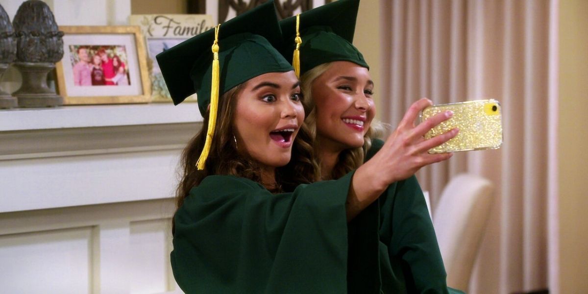 Alexa and Katie taking a selfie in their green cap and gowns on graduation day