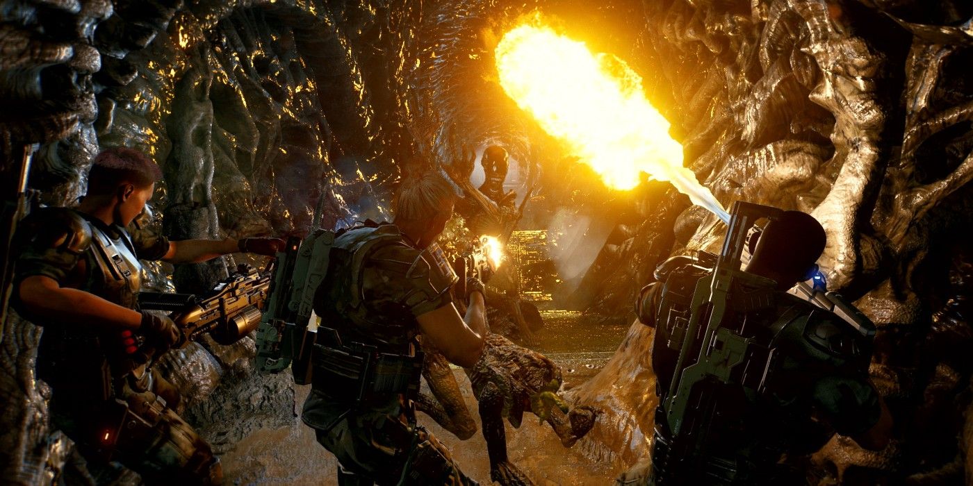 A squad in Aliens: Fireteam Elite standing side-by-side battling aliens, with one shooting a flamethrower.