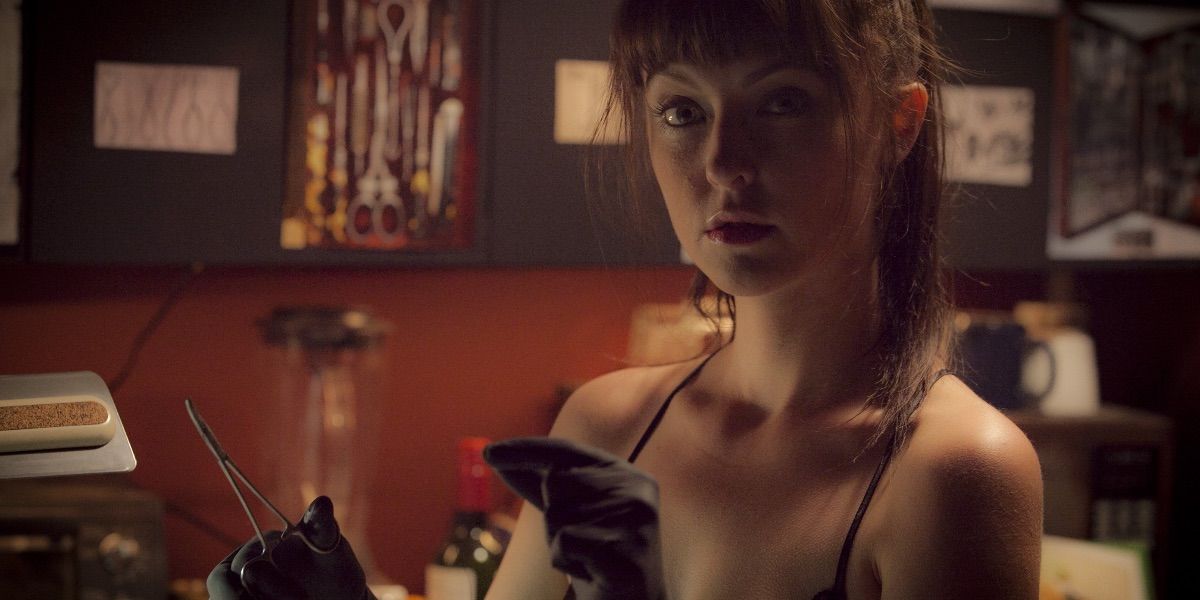 American Mary&rsquo;s Katharine Isabelle with gloves on, holding small surgical scissors