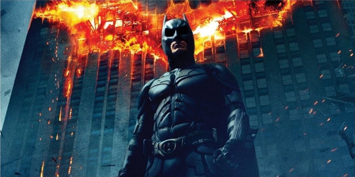 Batman stands in front of a burning building in The Dark Knight Poster
