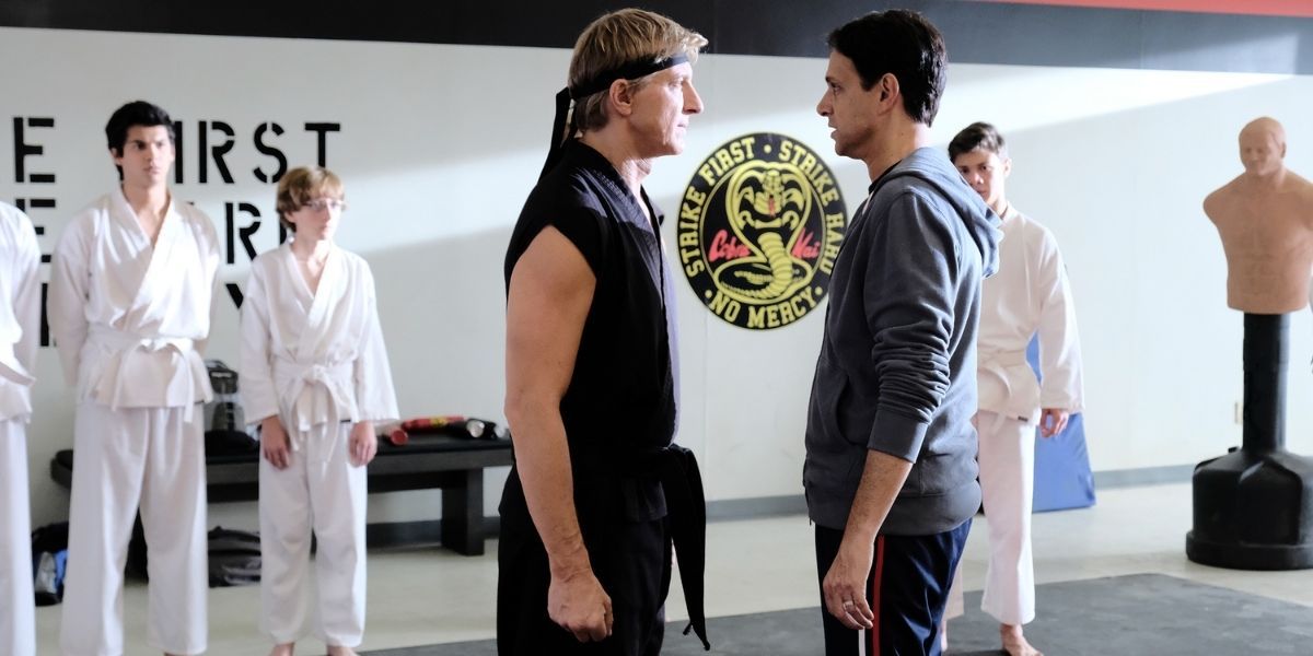 Daniel and Johnny and Danny stand and stare at each other in a dojo in Cobra Kai