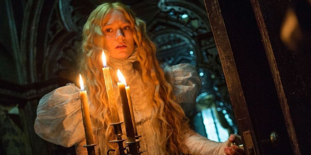 Mia Wasikowska's character Edith opening a door while holding a candelabra in Crimson Peak