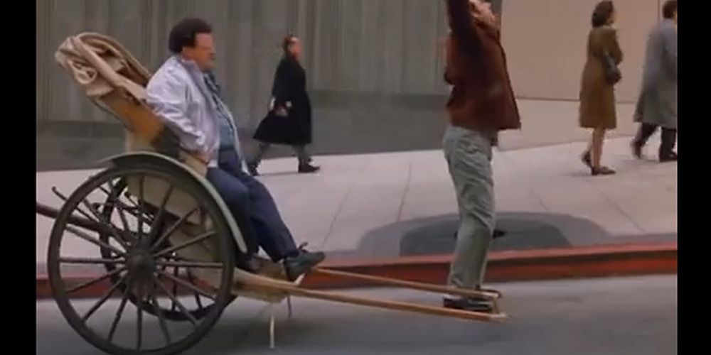 Kramer stretches as Newman sits in a rickshaw