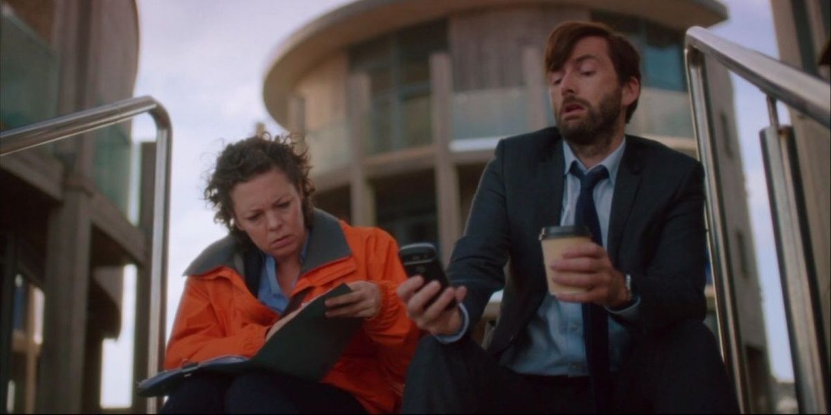 Ellie and Alec sitting side by side on some stairs in Broadchurch