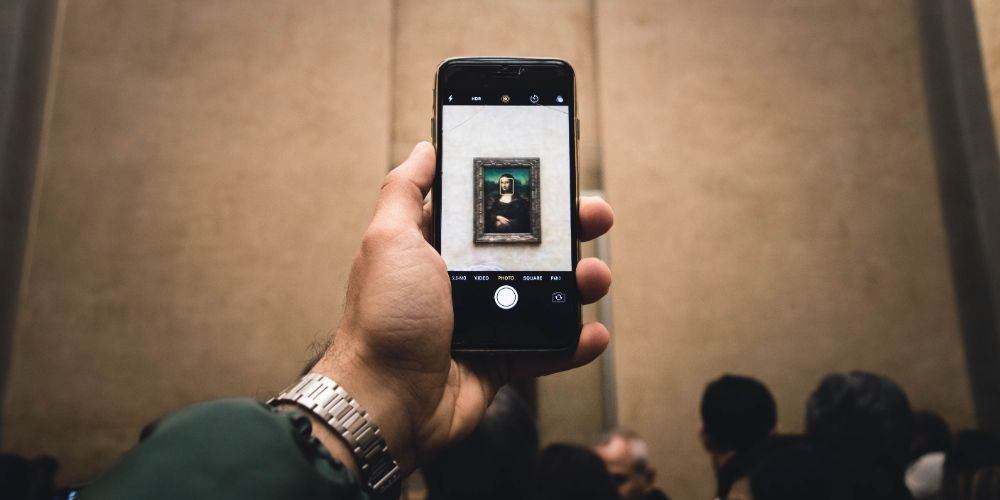 Someone holding their cell phone camera up to the Mona Lisa painting