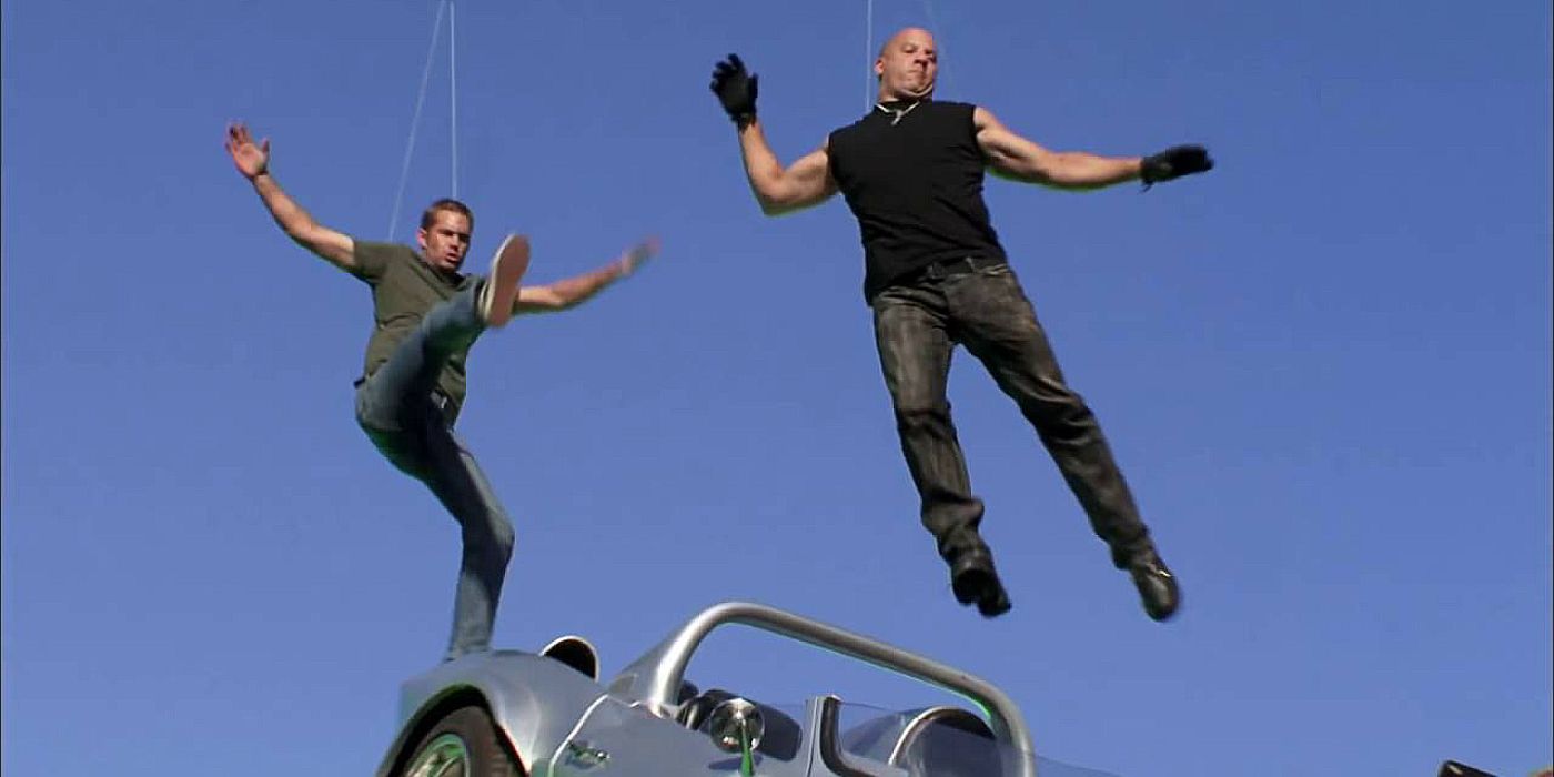 Paul Walker and Vin Diesel attached to wires behind the scenes of Fast Five