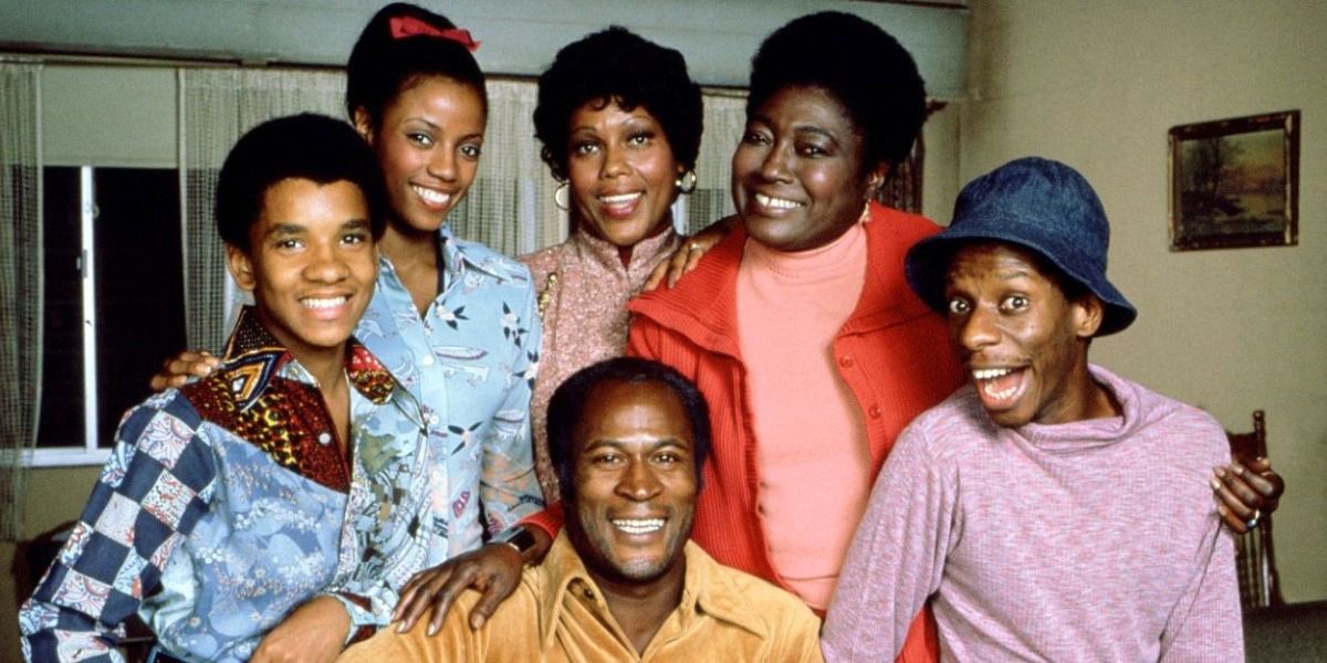Cast of Good Times smiling for the camera in their apartment with neighbor Willona