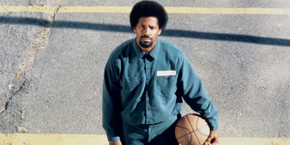 Denzel Washington tiene una palla da basket sotto il braccio in un campo in He Got Game