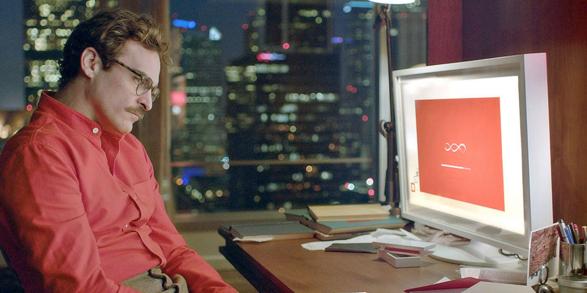 Joaquin Phoenix sitting with his head down in front of a computer in Her 