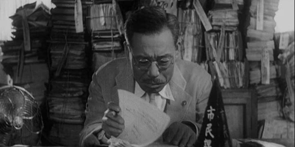 Scene from Ikiru with Mr. Watanabe looking through documents