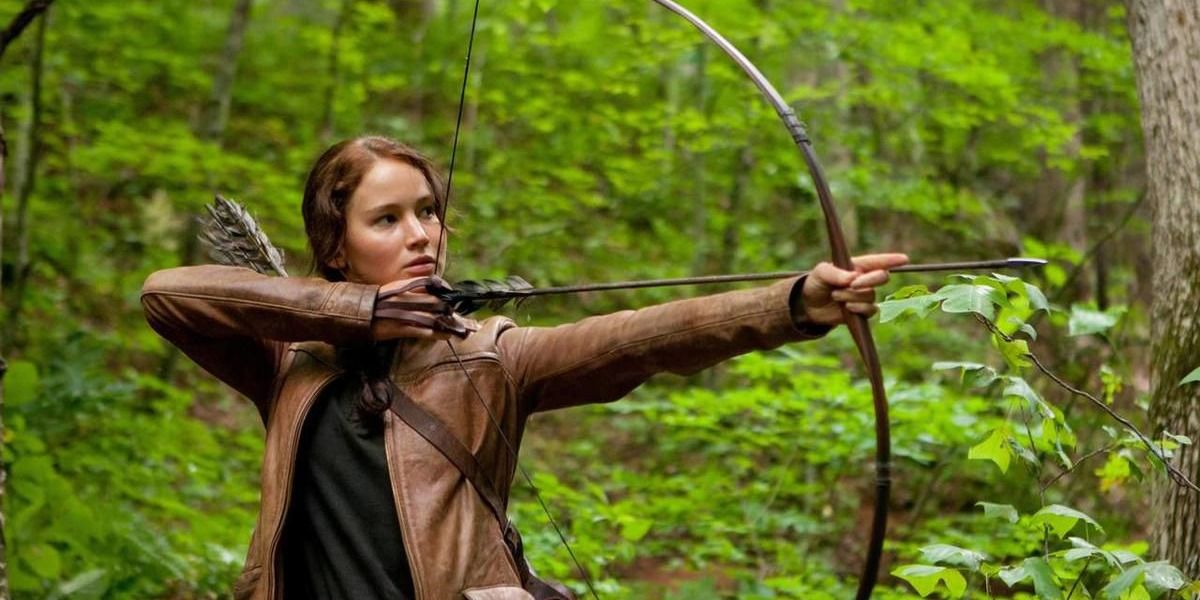 Katniss poiting her bow and arrow during one of her hunts