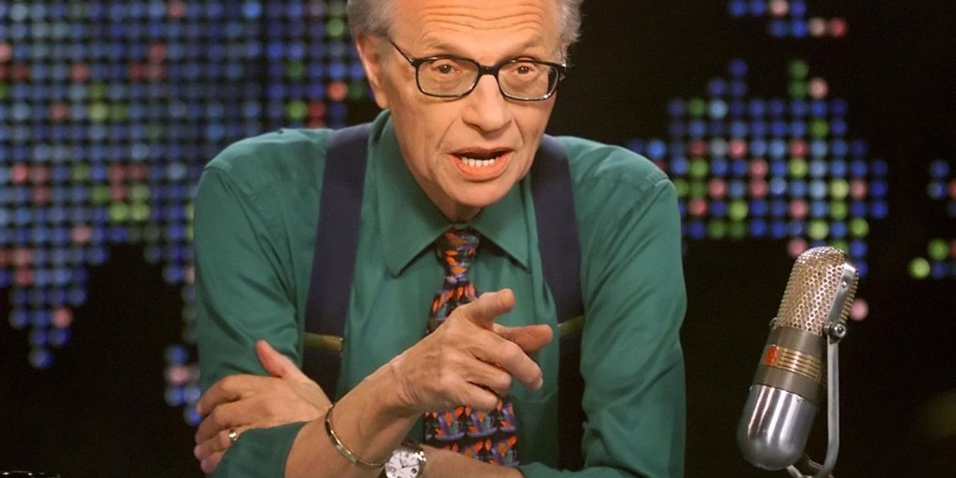 Larry King pointing finger with other hand on other arm, next to mic on Larry King Live