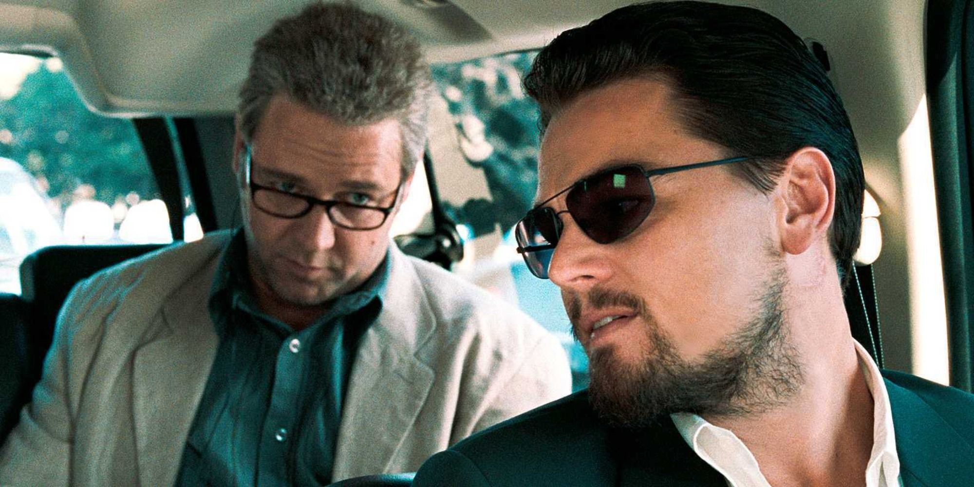 Leonardo DiCaprio leaning back to talk to Russell Crowe behind him in a car in Body of Lies