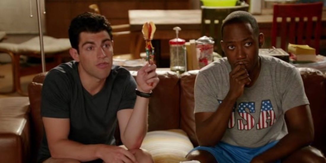 Schmidt holds the feelings stick during a discussion while Winston sits by him on the couch in New Girl
