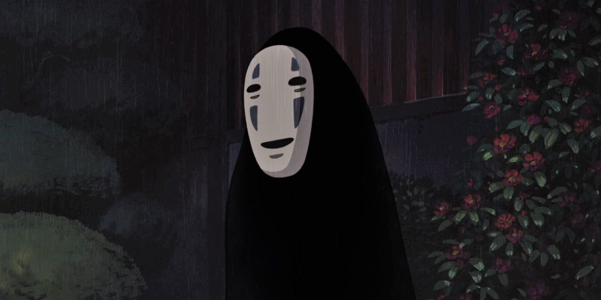 No Face from Spirited Away standing with dark background and smiling