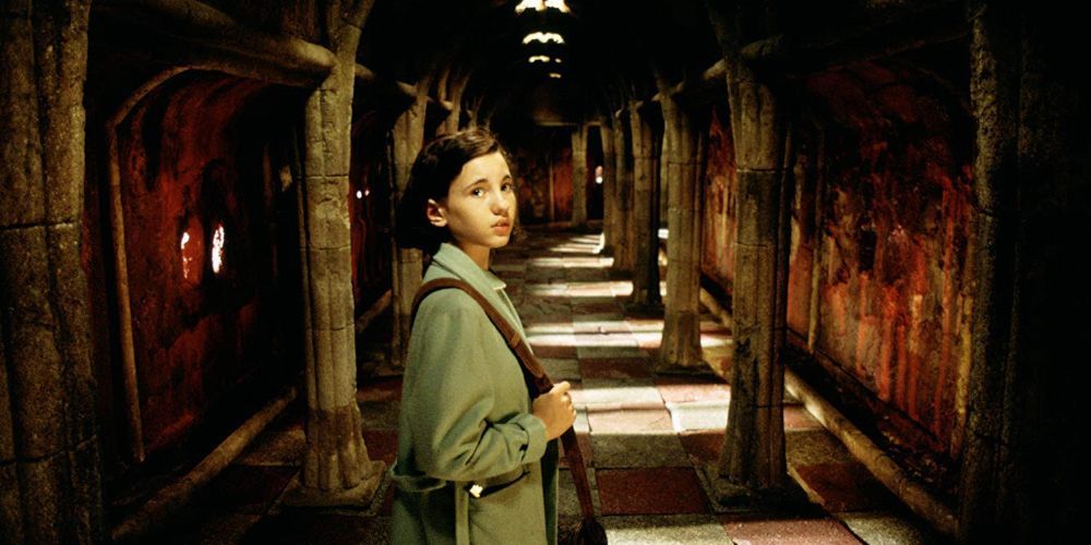 Ofelia looking behind her as she walks down a creepy corridor in Pan's Labyrinth