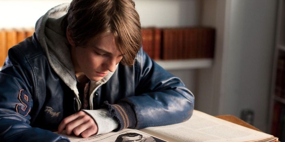Rufus looking at a book while sitting at a desk in the movie Rufus