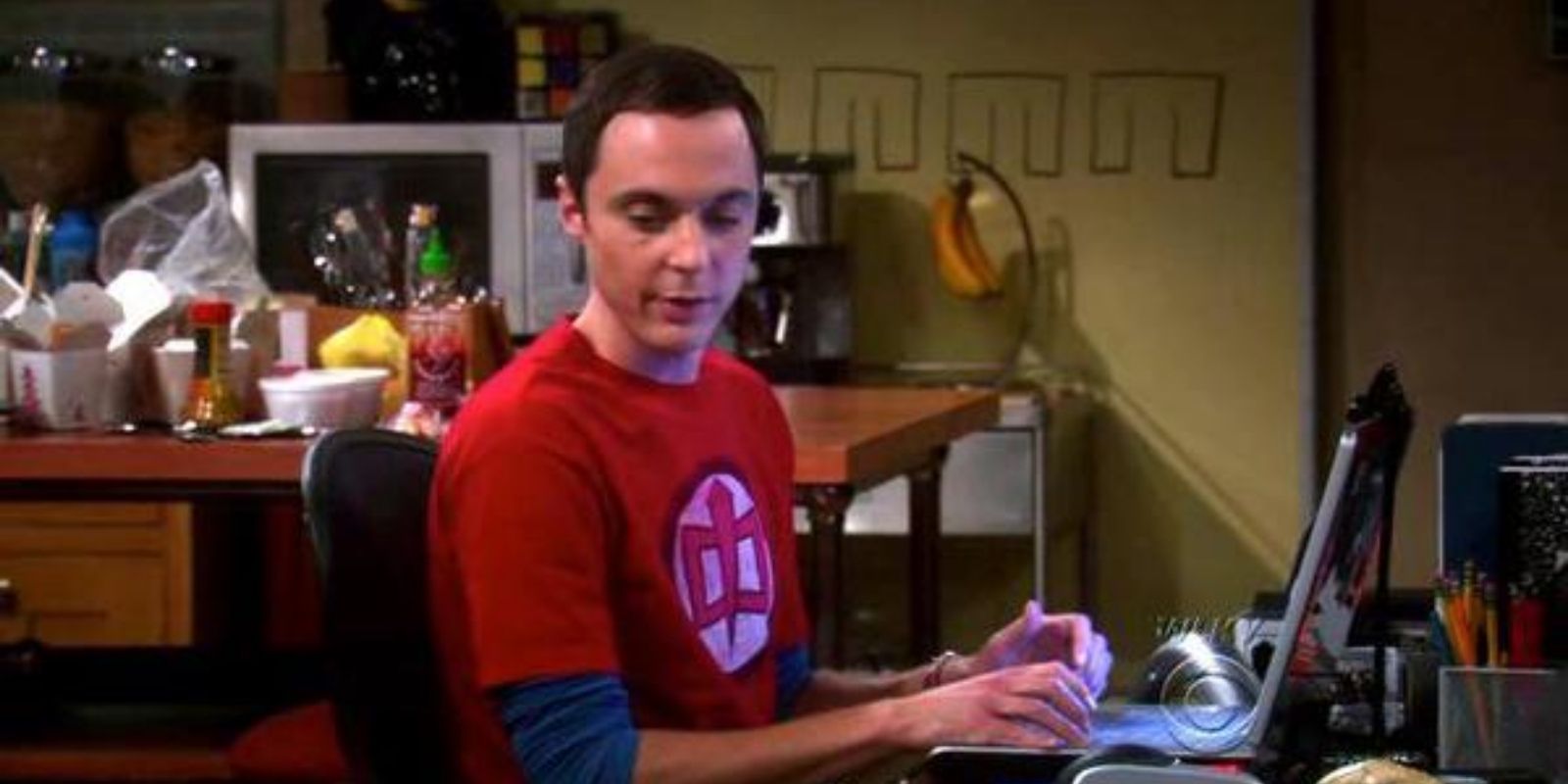 Sheldon Cooper wearing a red shirt with the logo of The Greatest American Hero in The Big Bang Theory