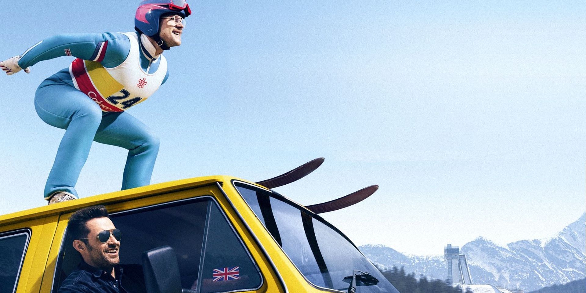 Taron Egerton standing on top of a car on skis in Eddie The Eagle