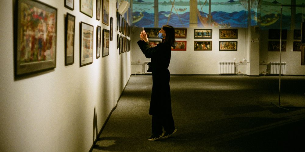 A woman taking a photo on an art gallery on her cell phone