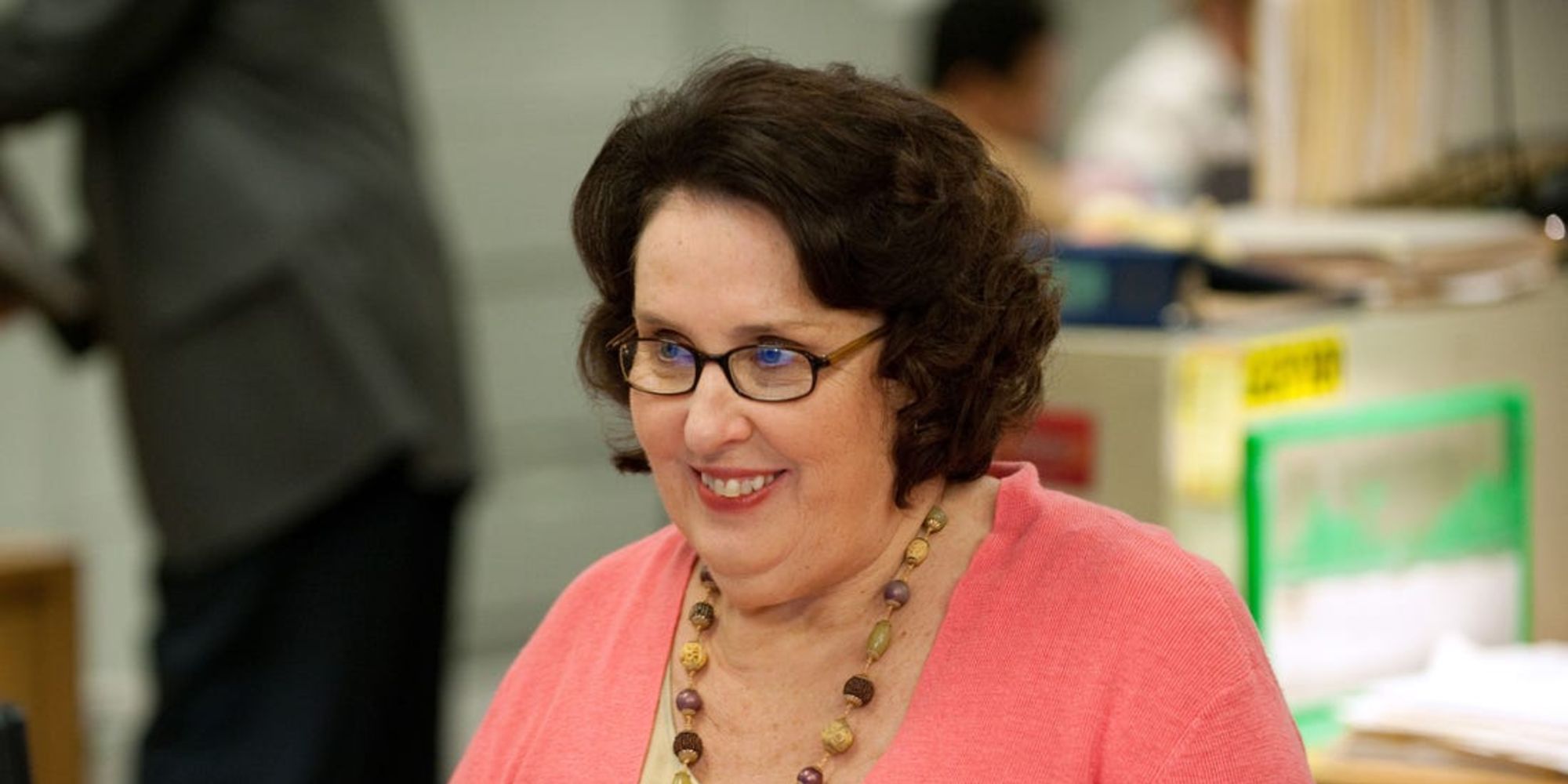 Phyllis Vance smiling while sitting at her desk at The Office