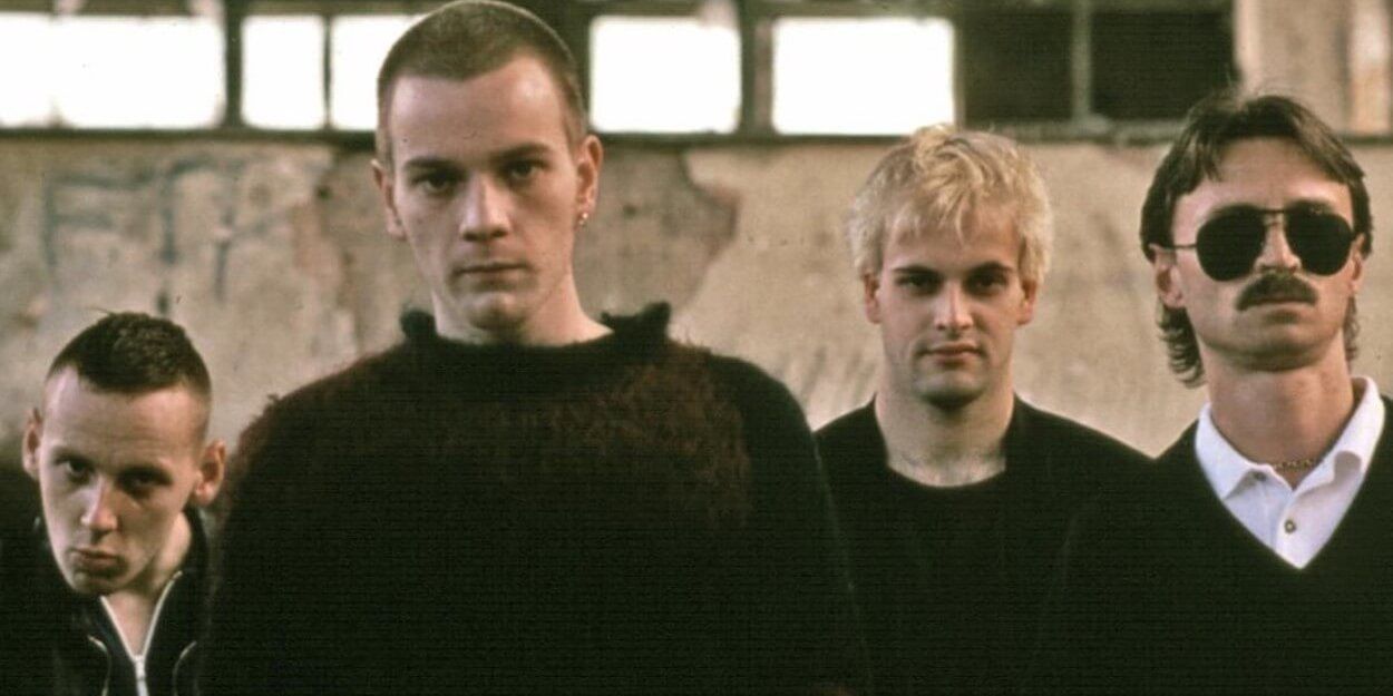 The four Trainspotting lads in black standing outside crumbling building