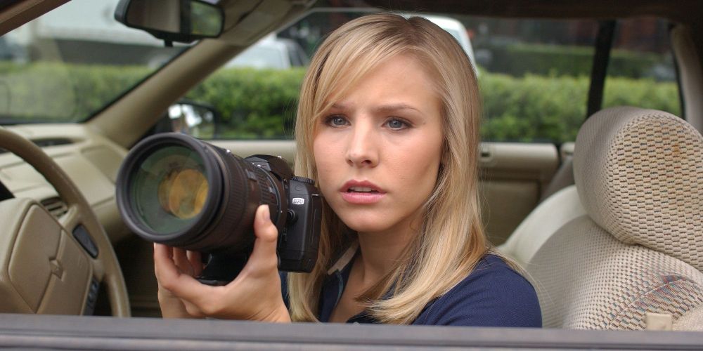 Veronica Mars taking photos with a camera from her car