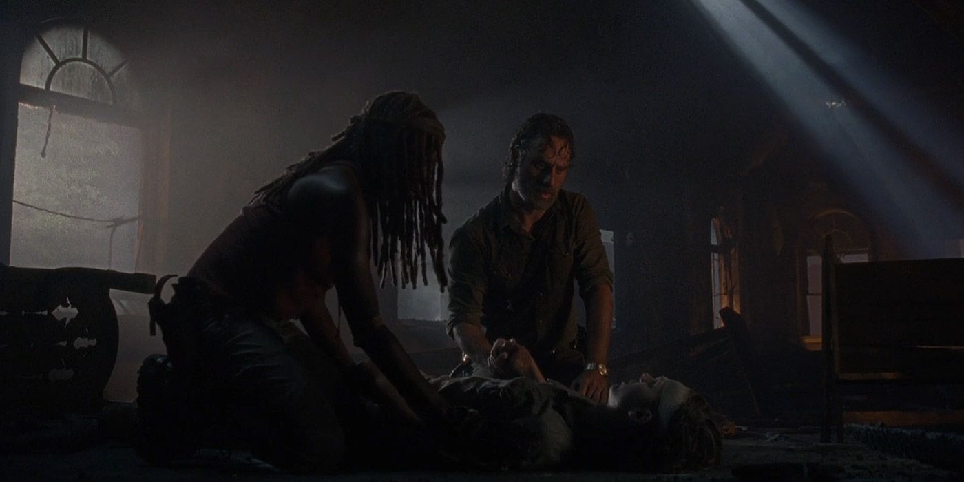 Michonne e Rick ajoelham-se sobre Carl moribundo em The Walking Dead