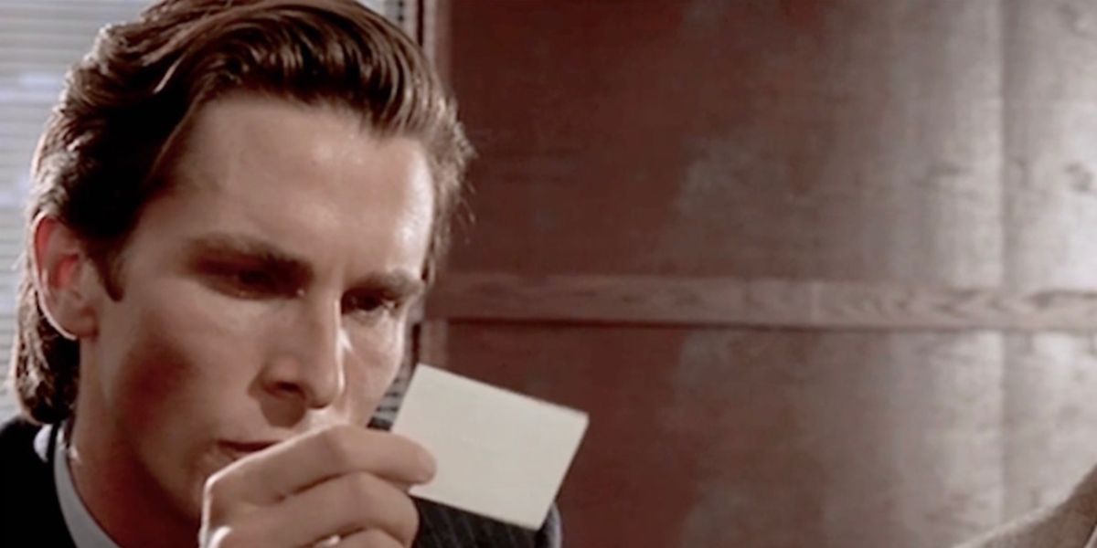 Christian Bale as Patrick Bateman in American Psycho staring at a business card given to him by one of his associates on Wall Street, examining the perfect printing and texture