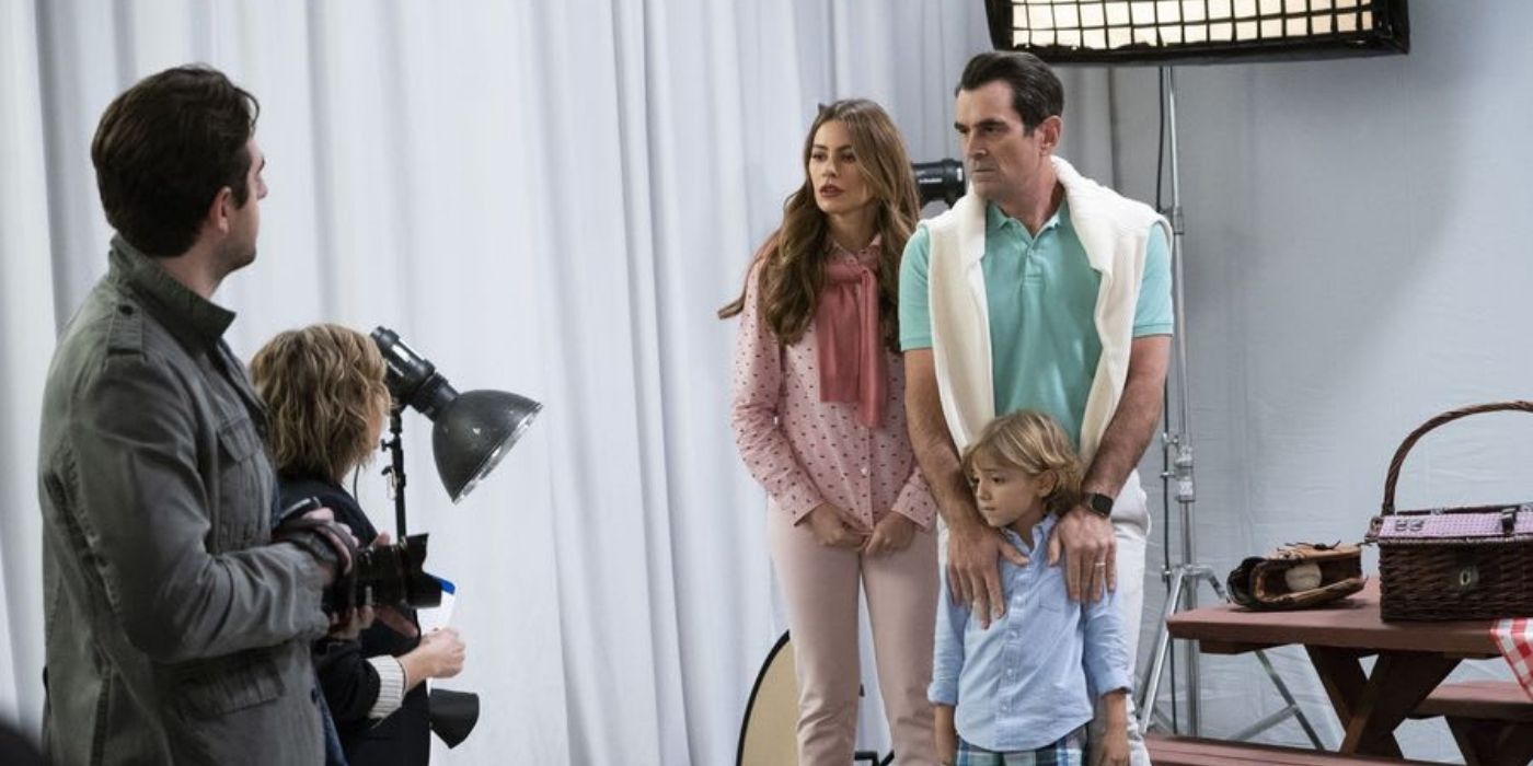 Gloria and Phil posing for a family portrait with Joe on Modern Family