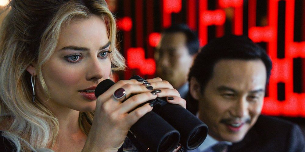 Margot Robbie's Jess peering through binoculars in Focus
