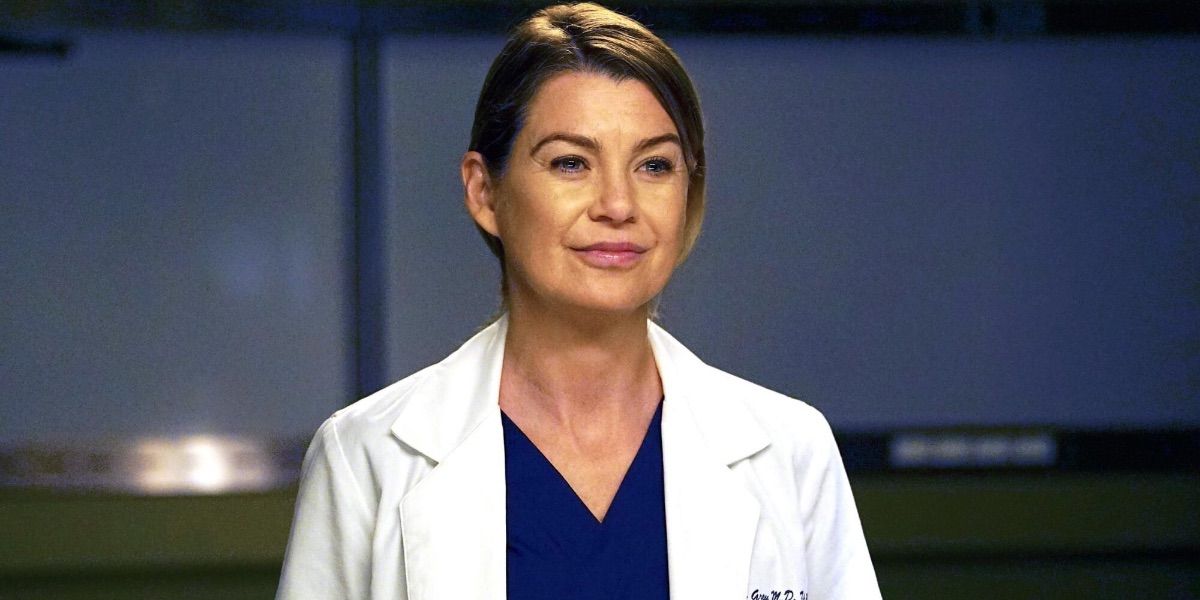 Meredith in her navy blue scrubs and white labs coat, smiling at someone off-screen