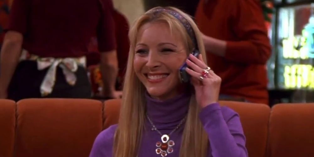 Lisa Kudrow on Central Perk sofa on mobile phone and smiling