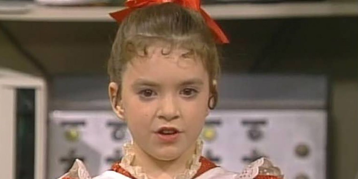 Vicki from Small wonder with her hair up and red bow with signature red outfit and white apron