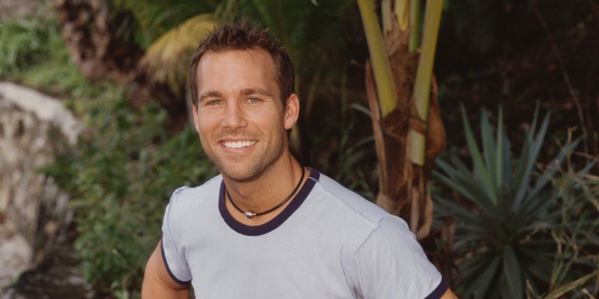 Colby from Survivor wearing a white T-shirt and smiling.