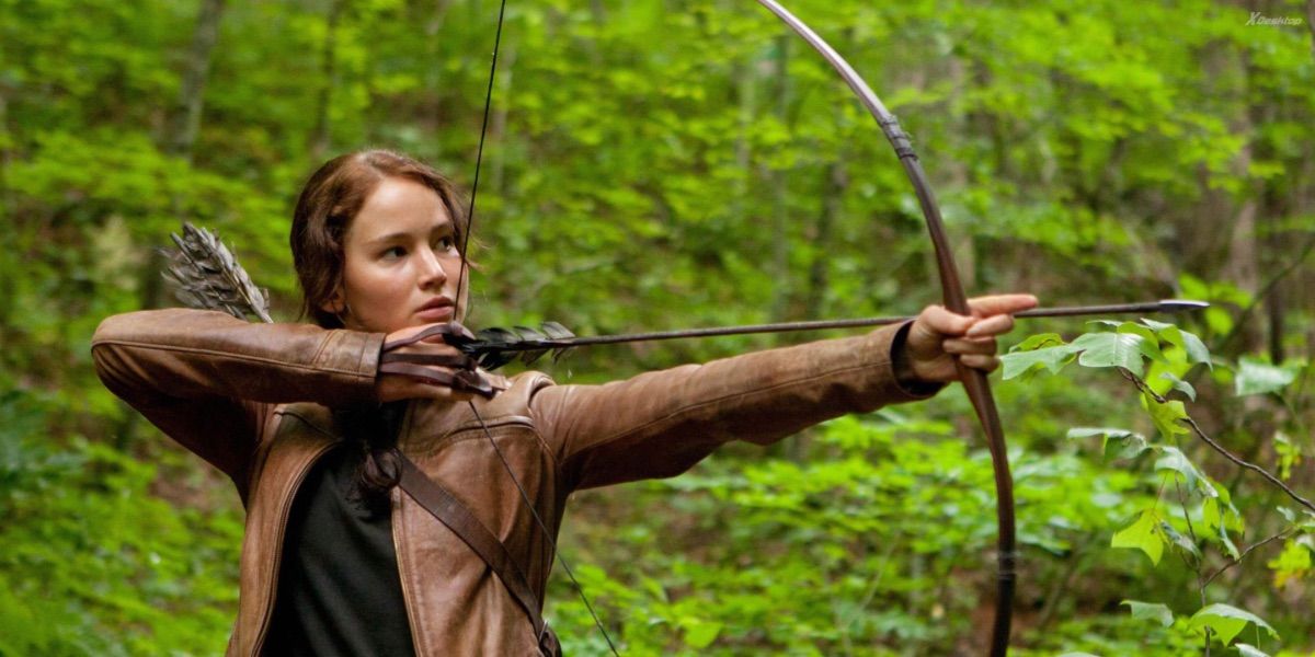 Katniss draws her bow and perpares to fire to the right of the screen in The Hunger Games