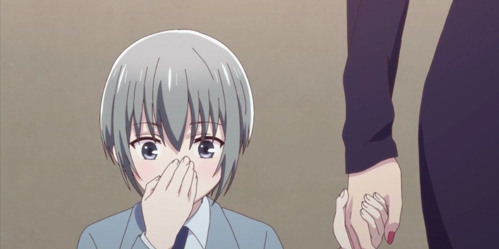A young Yuki holding his hand over his mouth.
