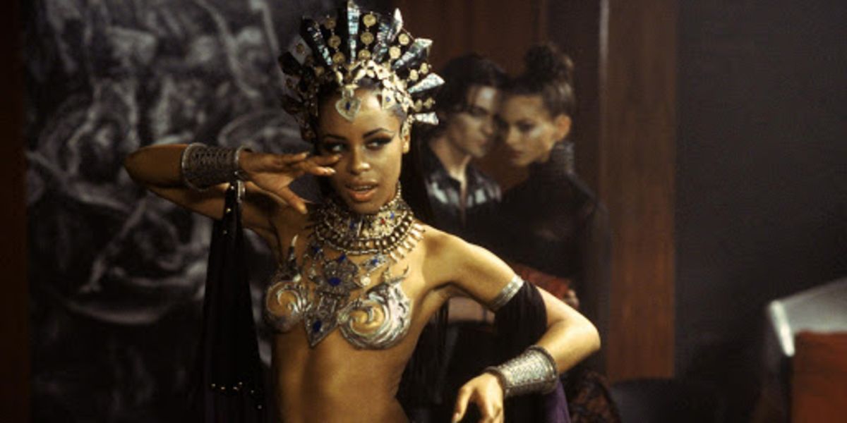 Akasha (Aaliyah) in golden top and crown among the vampires in Queen of the Damned