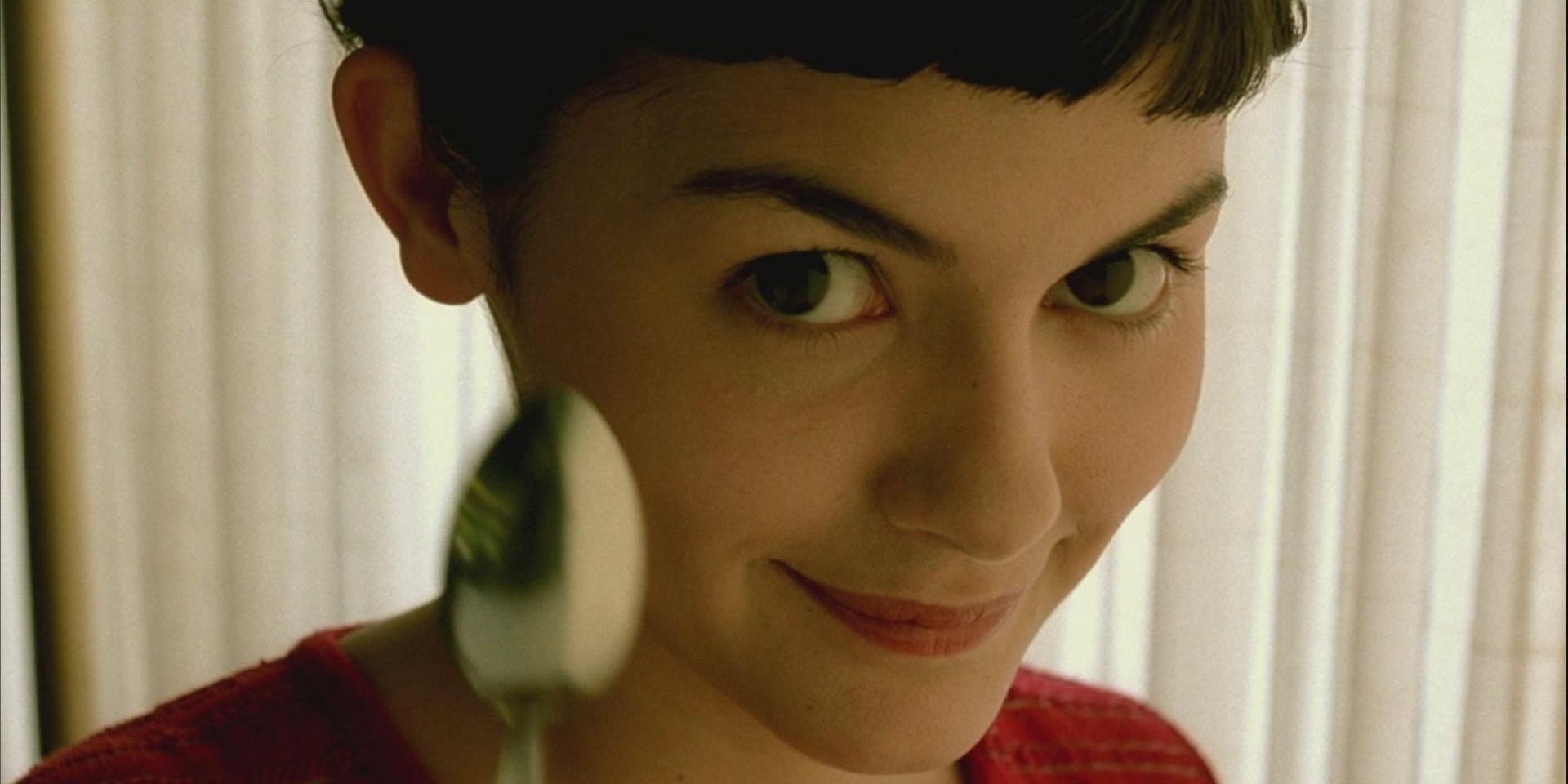 Audrey Tautou in Amelie holding a spoon and smiling at camera.