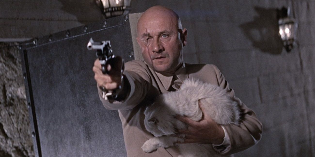 Donald Pleasance as Ernst Blofeld holding a gun