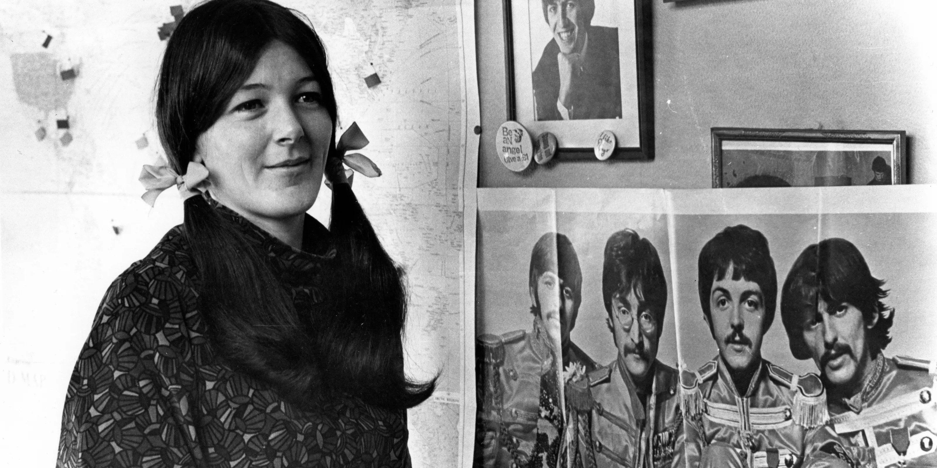Freda Kelly posing next to a Beatles poster 