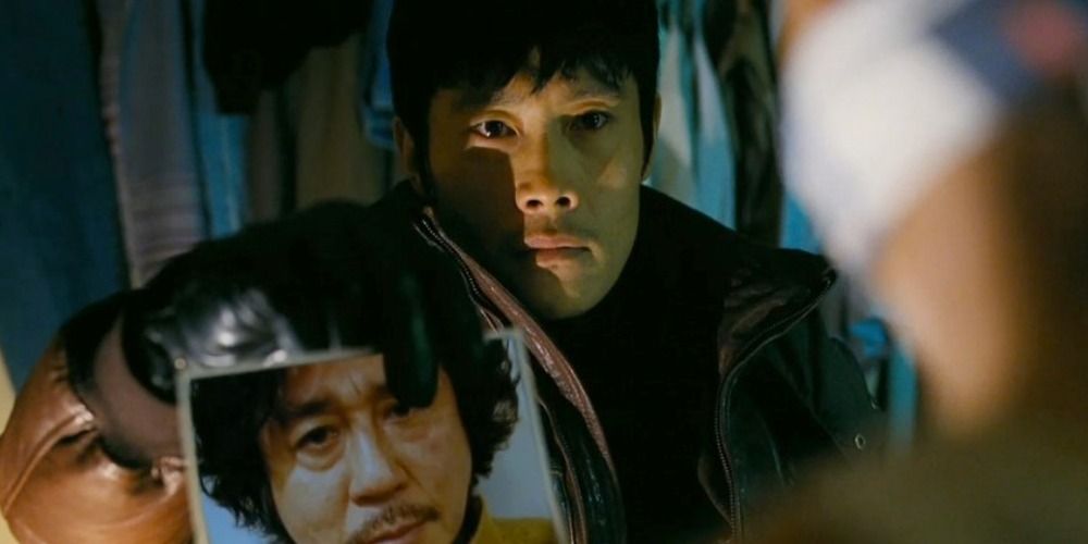 Kim Soo-heyon holding up a picture of a missing man to someone off-camera in I Saw The Devil
